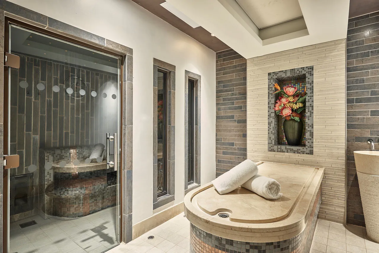 A spa treatment room with a stone bench and rolled towels.