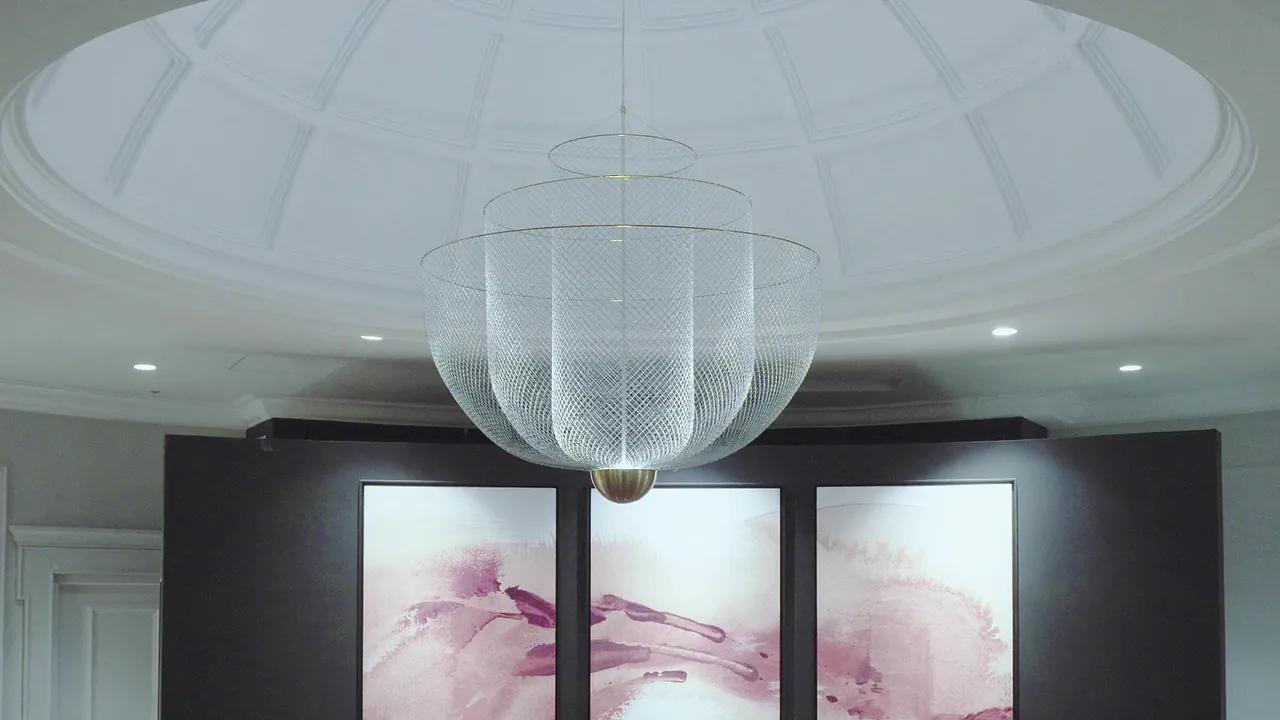 A domed lobby ceiling with a large glass chandelier and pink abstract artworks.