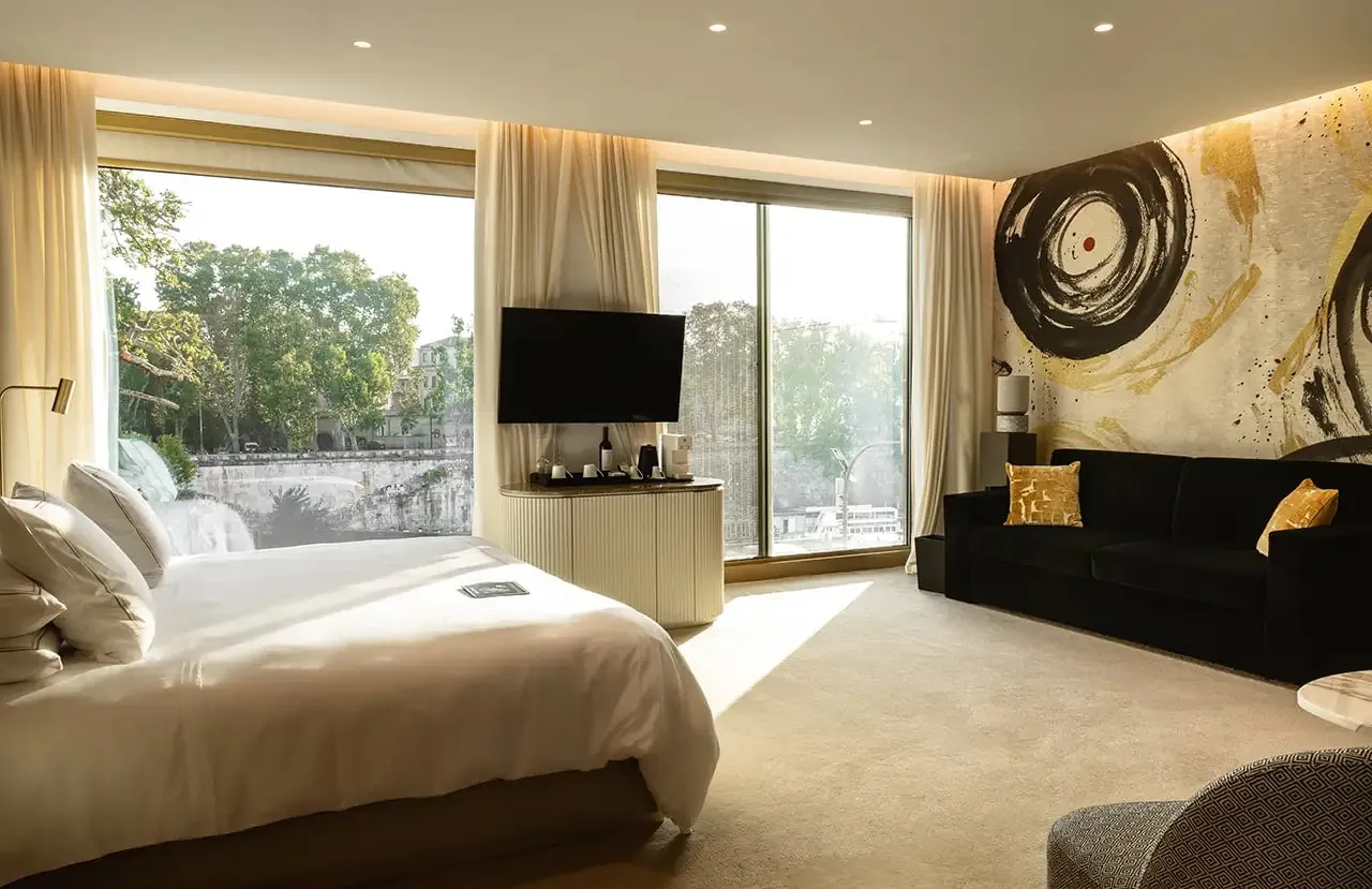 Junior suite with a sofa, a bold artwork and wide windows over the trees.