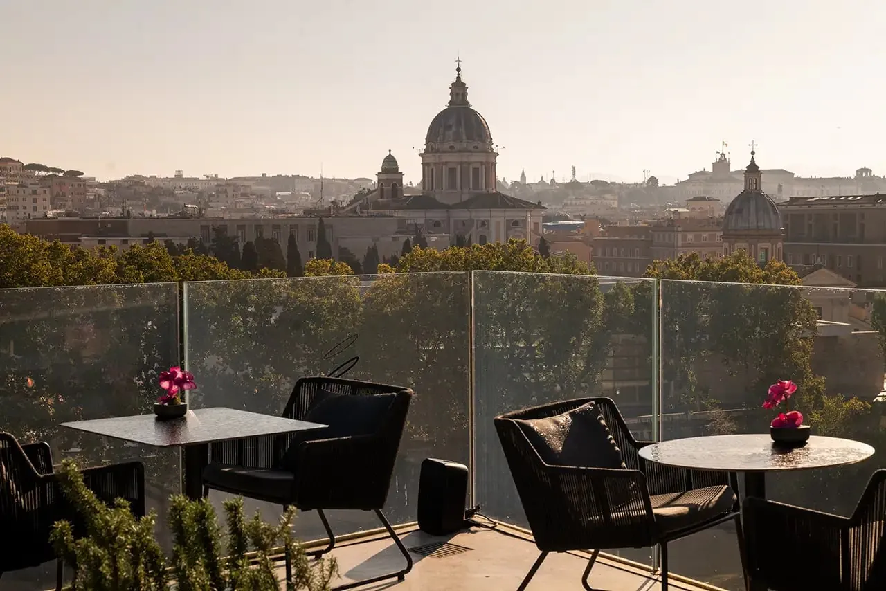 Rooftop terrace tables with a view of a church dome at sunset.