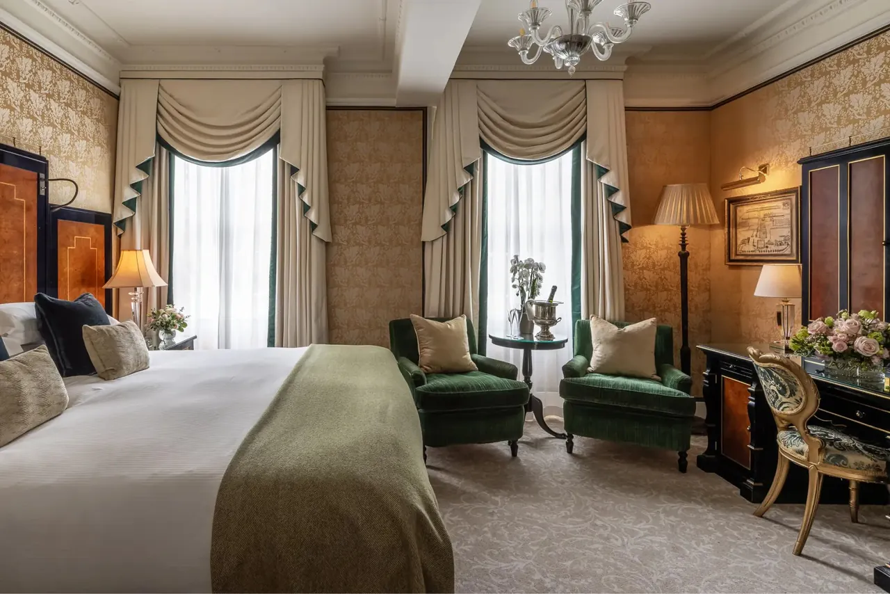 A deluxe room with wood panelling, armchairs and a view of the garden.