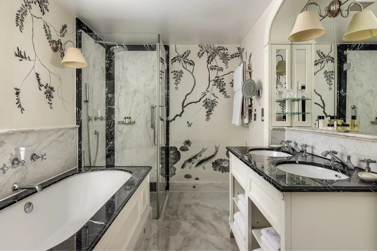 A marble bathroom with a bathtub and hand-painted wallpaper.