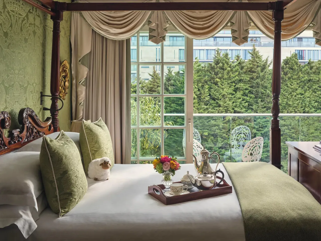 A four-poster bed facing tall windows that open onto the trees.