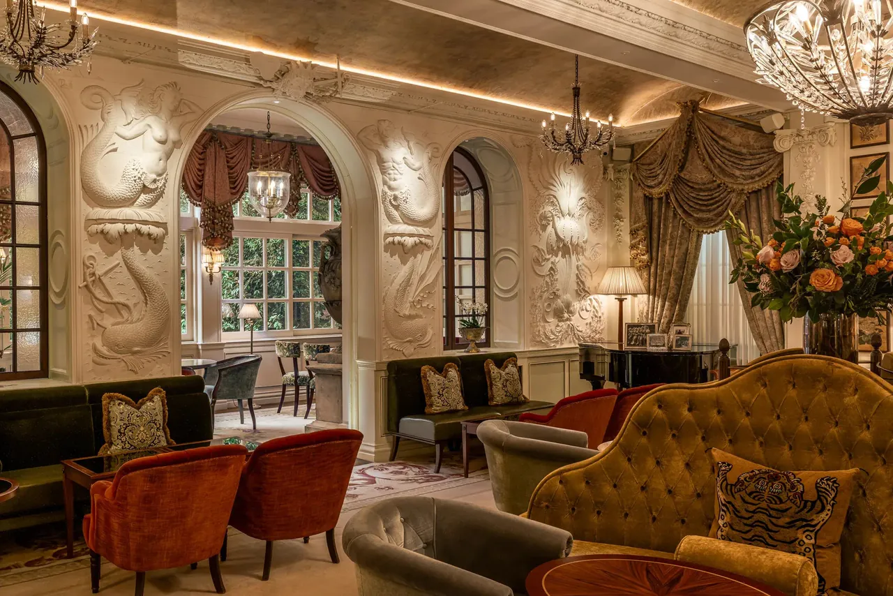 The bar lounge with carved white plasterwork and plush red seating.