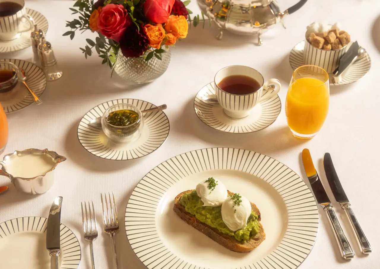 Breakfast with avocado toast, tea and orange juice on white linen.
