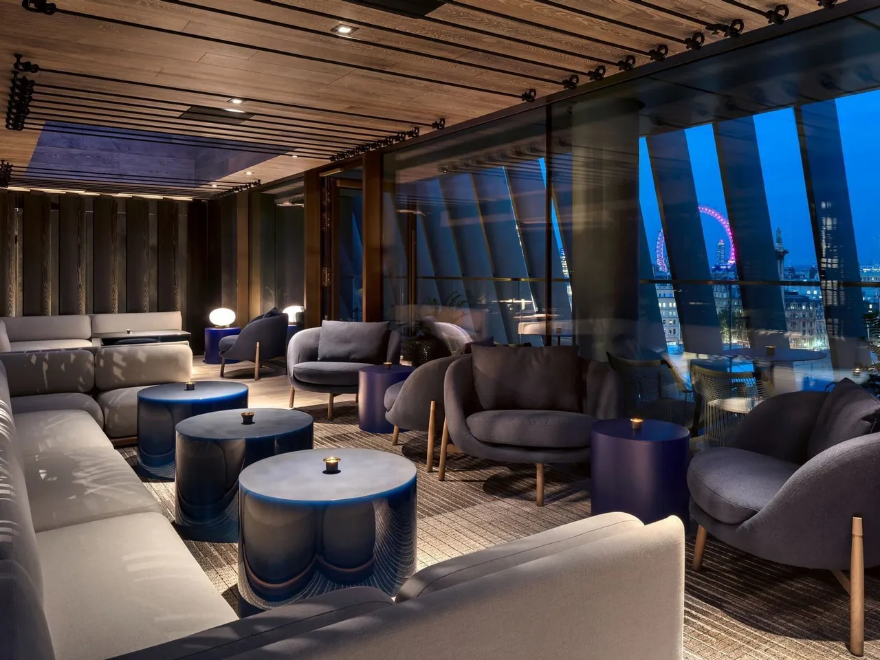 The rooftop bar 8 at The Londoner with lounge seating and a view of the London Eye.