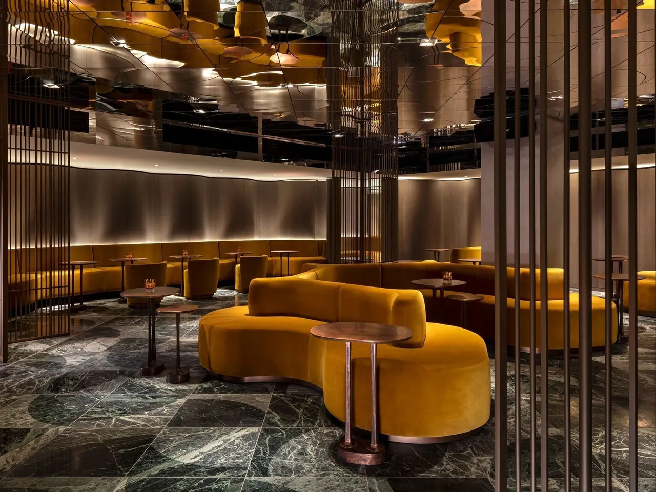 The Green House lounge with curved yellow velvet seating and a mirrored ceiling.