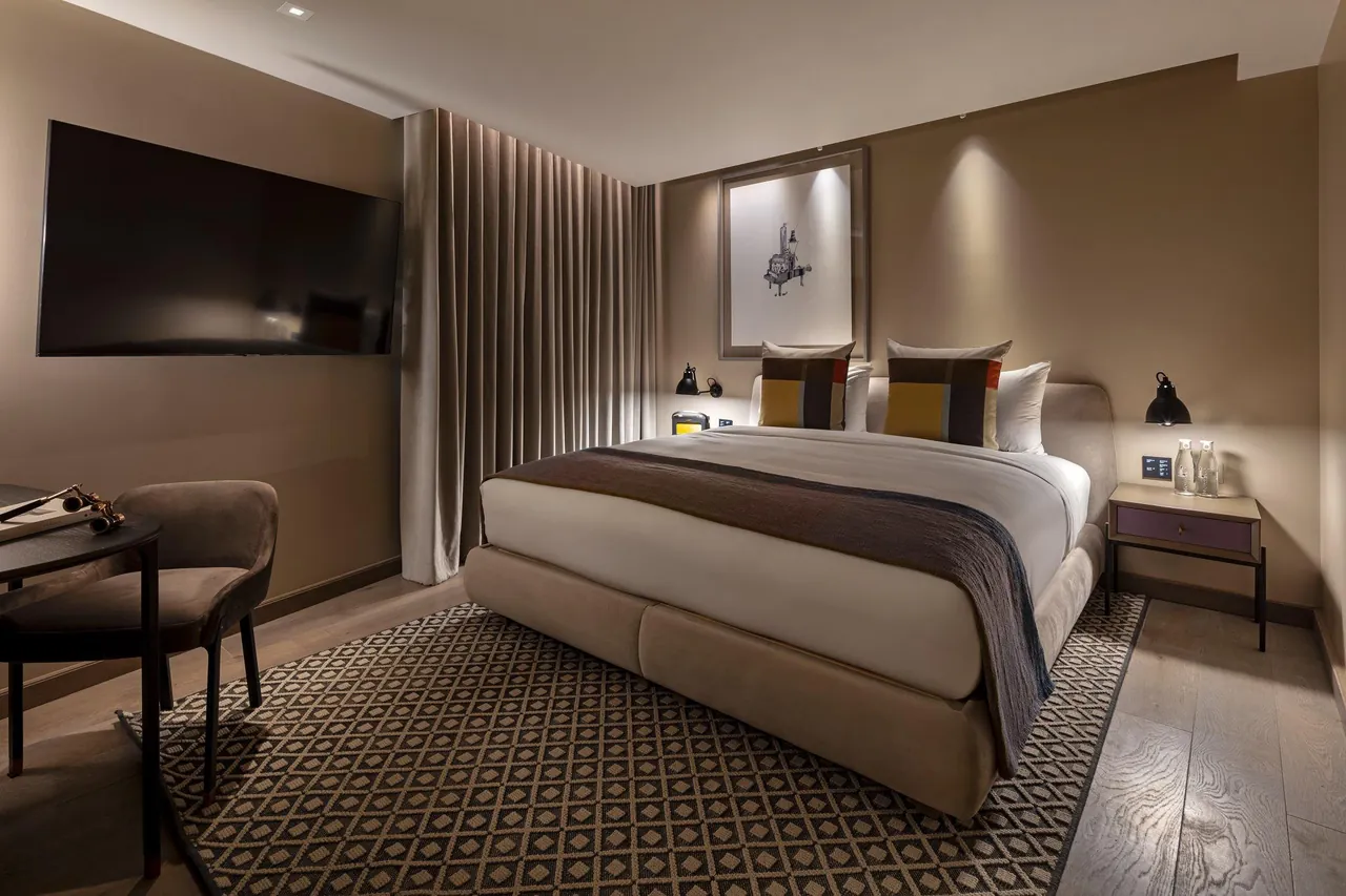 A calm guest room with a large bed in soft grey and wood tones.