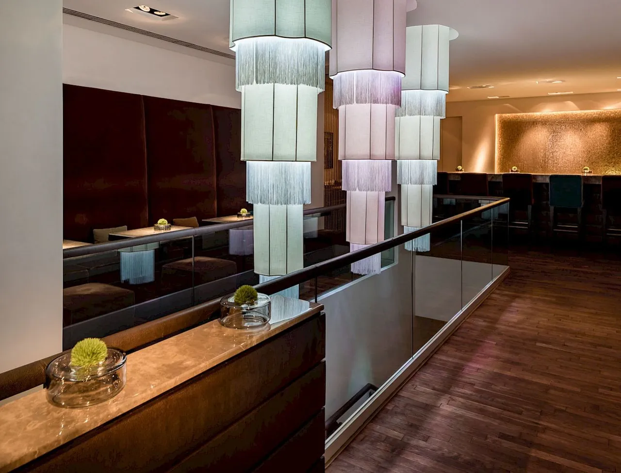A dark wood bar lit by tall glass chandeliers.