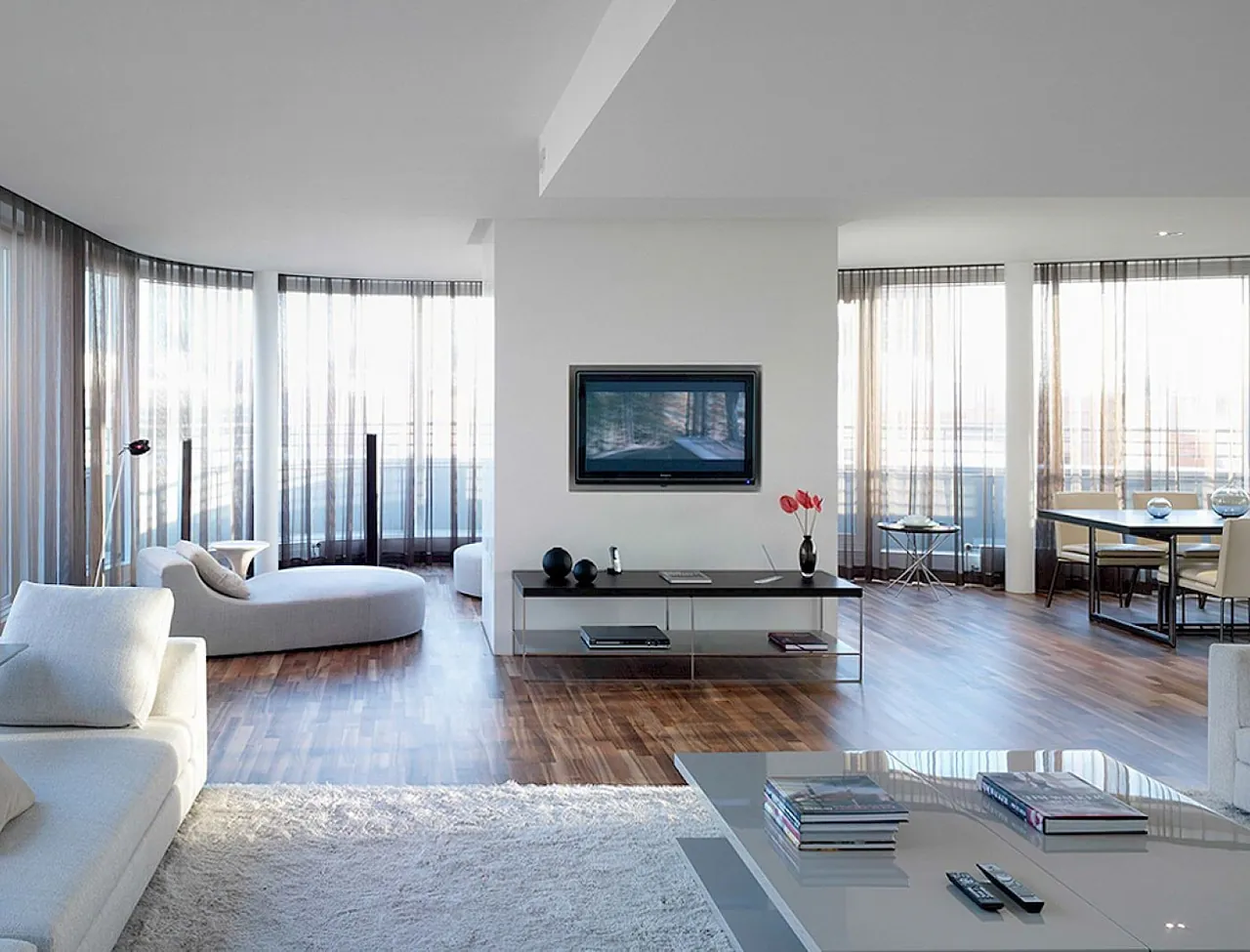 An open-plan suite living room with wooden floors and wraparound windows.