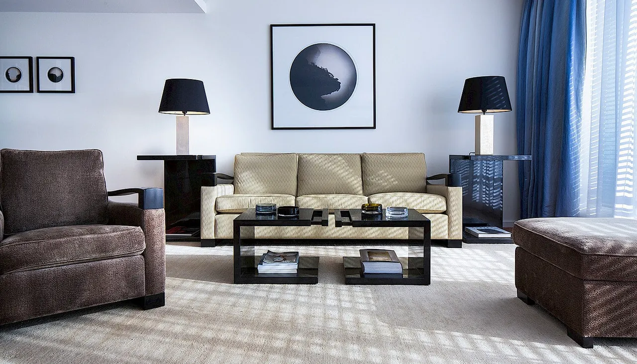 A living room with a cream sofa, dark accents and blue curtains.