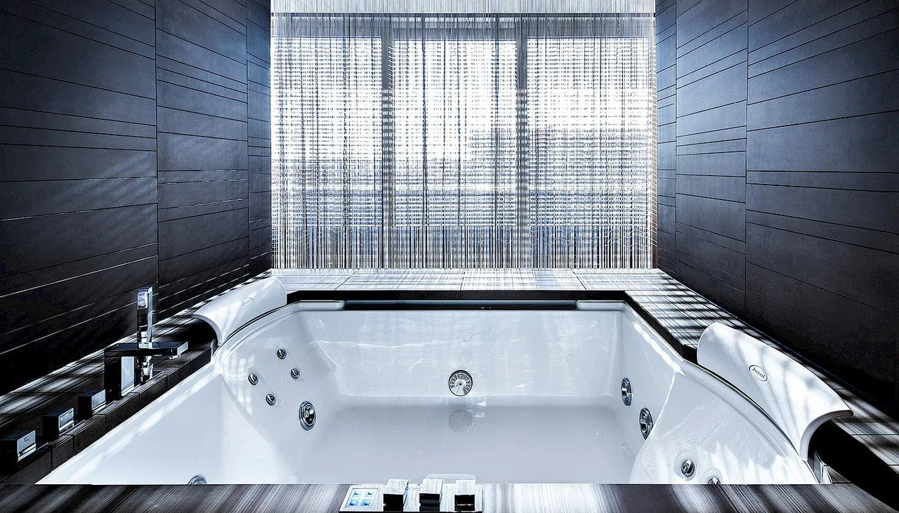 A large whirlpool tub in front of a window in the penthouse.