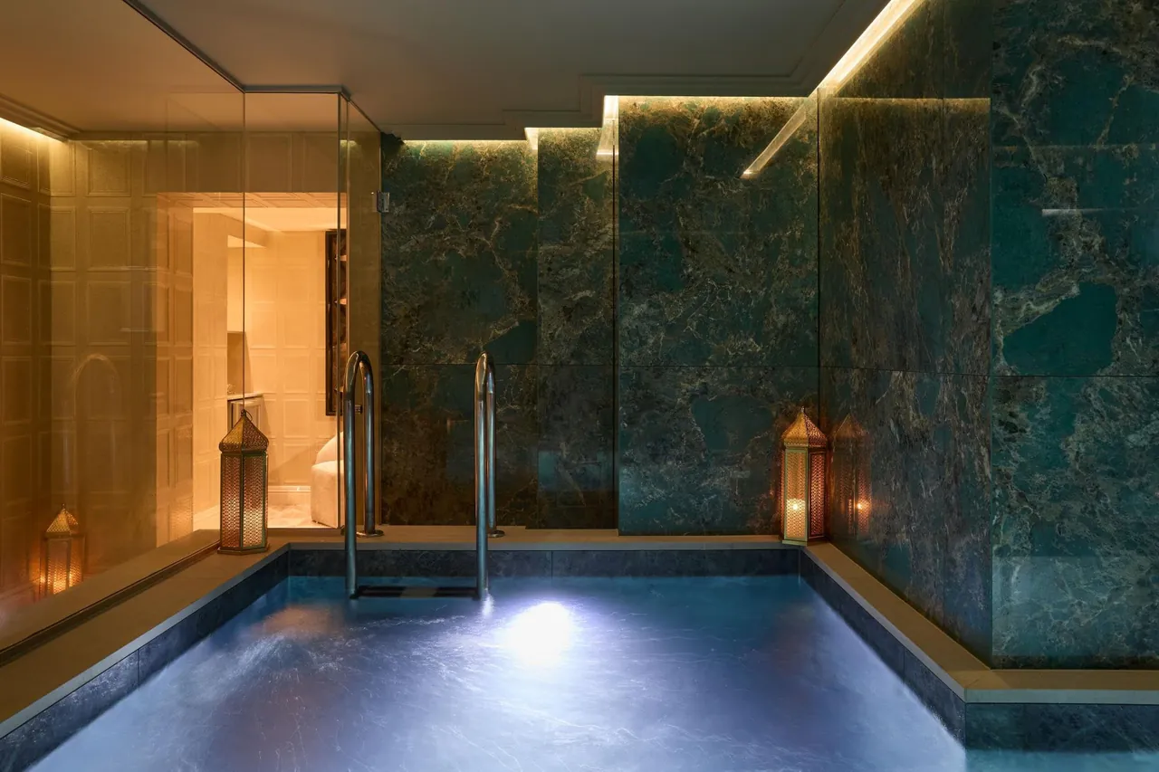 The indoor pool lined with green stone under soft warm lighting.