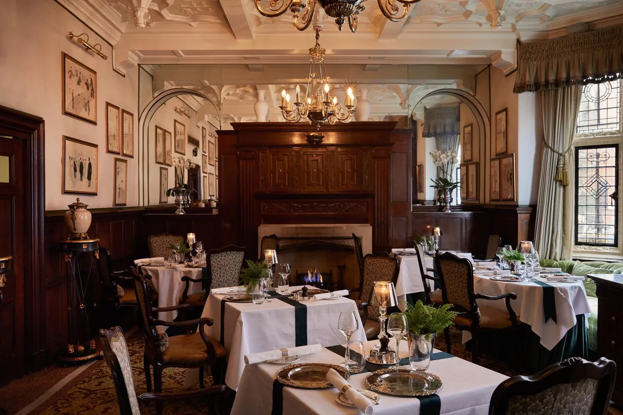 The wood panelled dining room with white tablecloths and a chandelier.