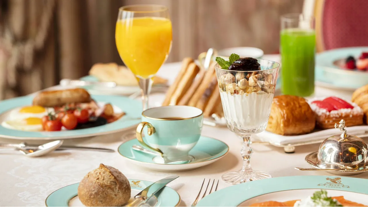 A breakfast table with fresh juice, pastries and fruit.
