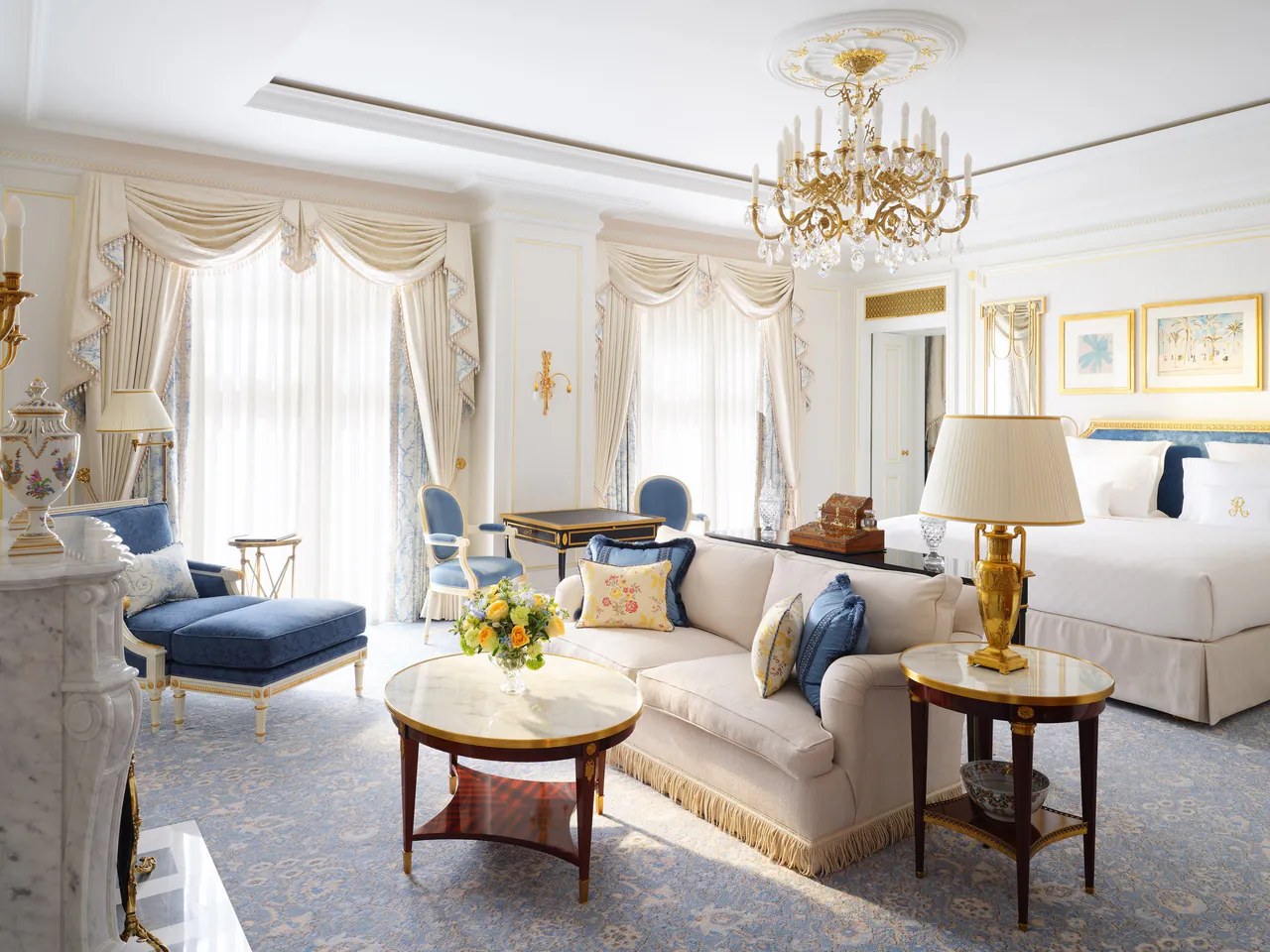 A Junior Suite with a chandelier, blue armchairs and a cream sofa.