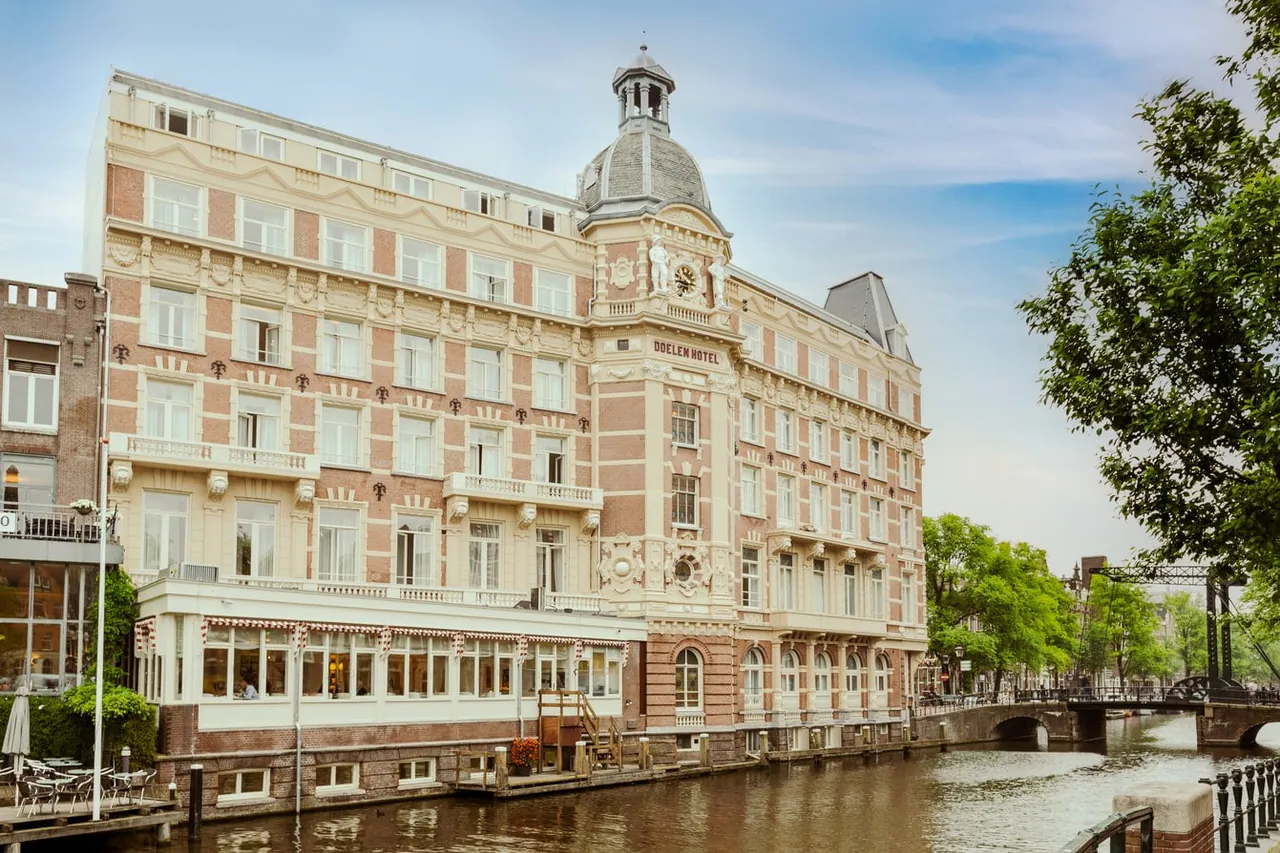The ornate sandstone facade of the hotel with its domed corner tower beside the Amstel.