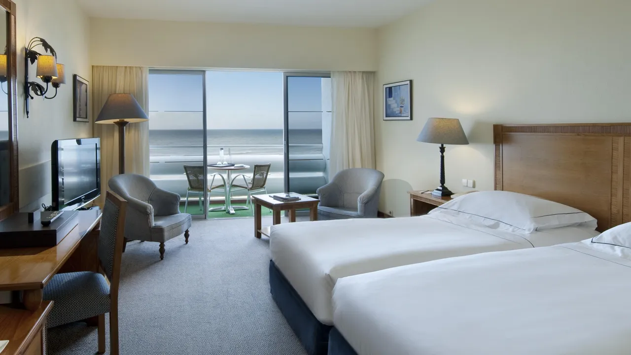 Twin room at Tivoli Marina Vilamoura with armchairs and a balcony table and chairs facing the sea