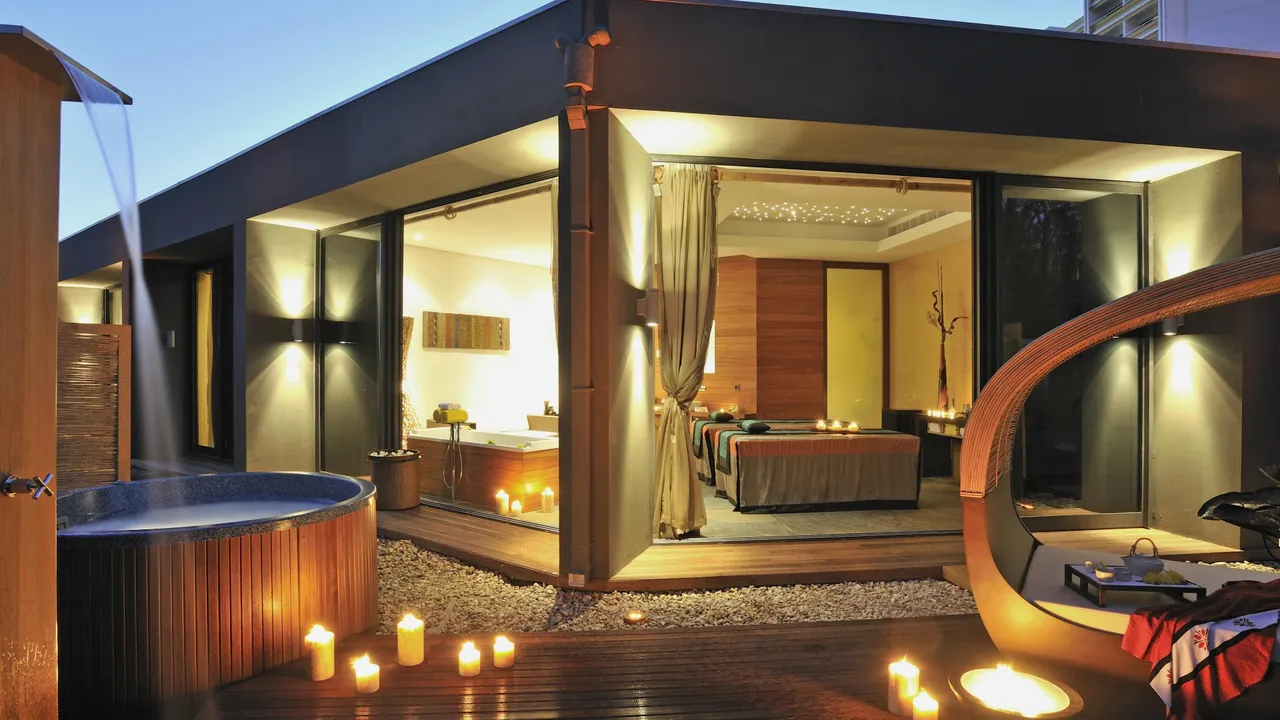 Spa terrace at Tivoli Marina Vilamoura at dusk with candles, a wooden hot tub and treatment room